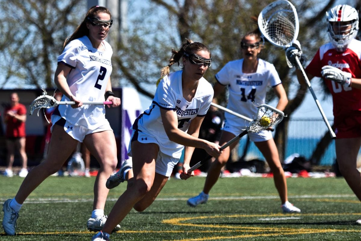 A Northwestern lacrosse player wearing white runs with the ball.