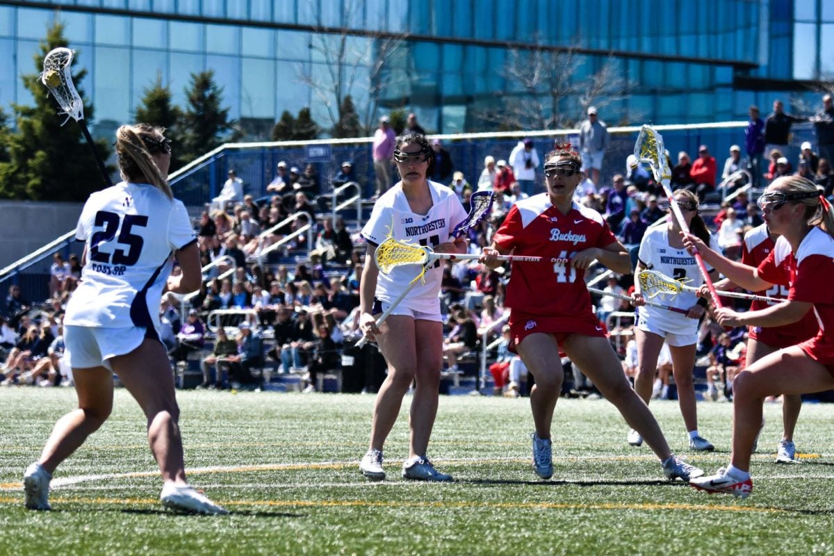 A Northwestern lacrosse player looks to pass the ball as other players look on.