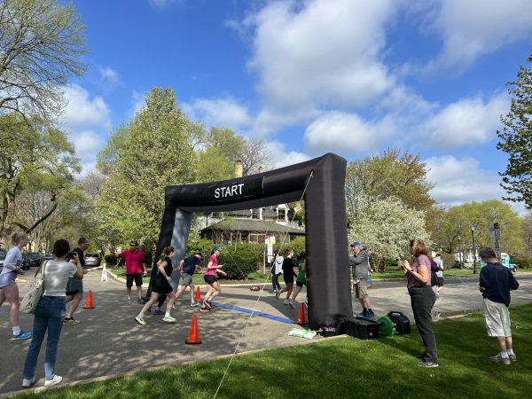 People run through an inflatable start line on a road.