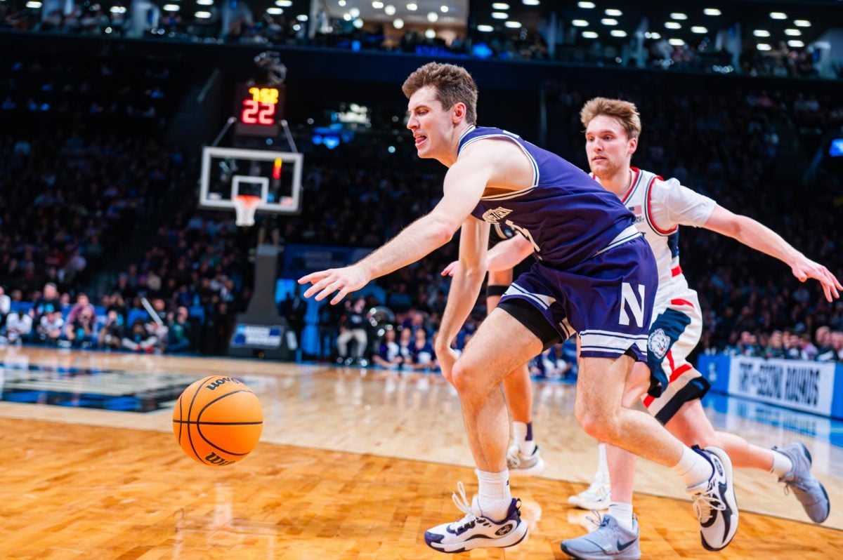 A basketball player in purple reaches out for the ball.
