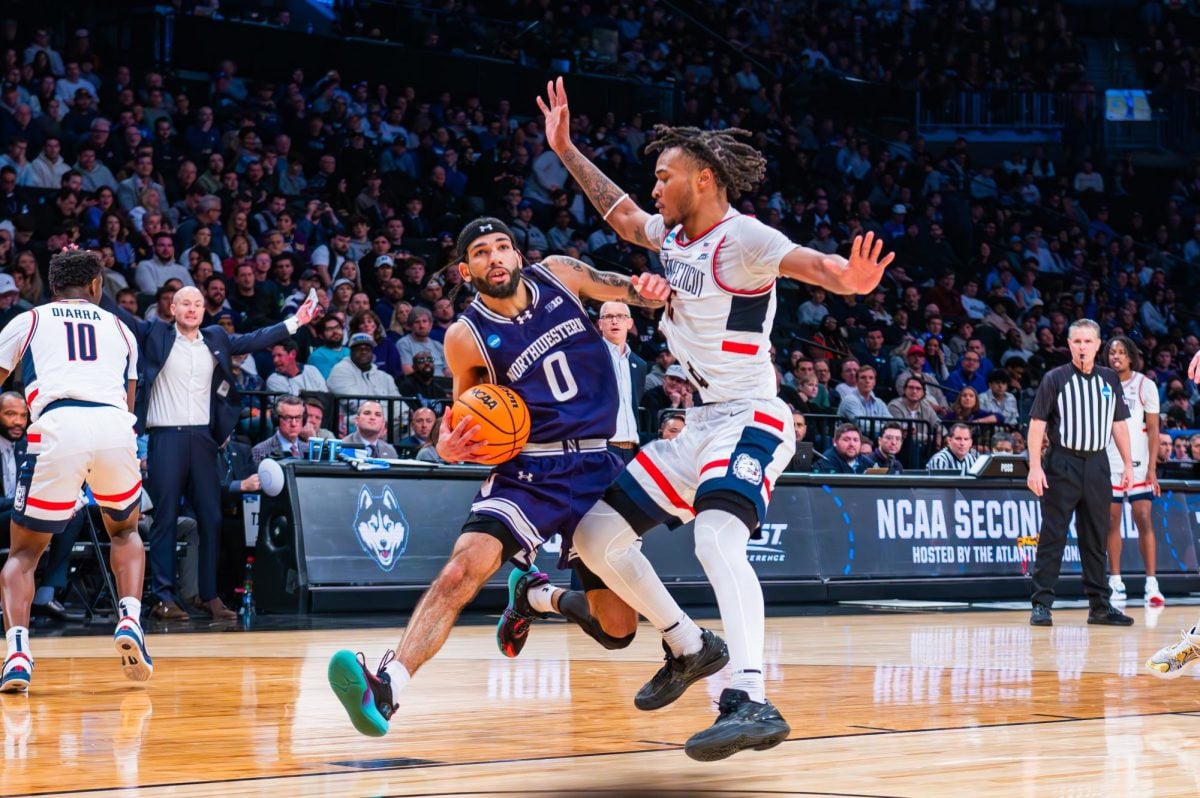 A basketball player in purple pushes an opposing team player while holding the ball with their right hand.