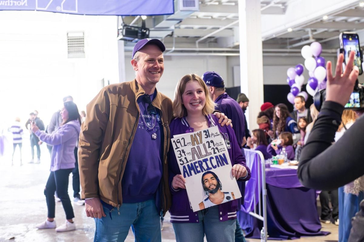Two people pose for a photo, with one of those people holding up a poster of Northwestern basketball player Boo Buie.