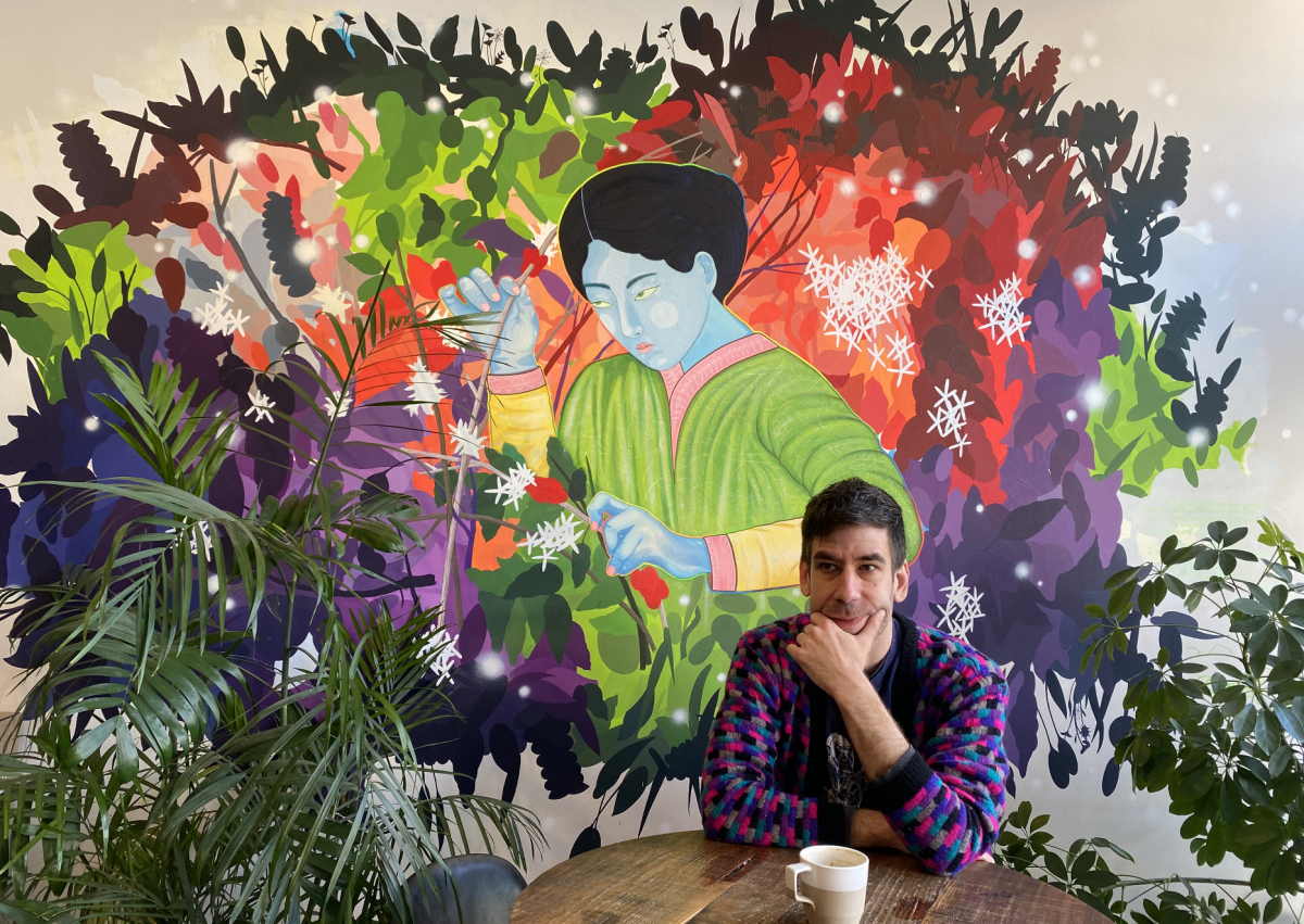 Daniel Burnett in front of his mural inside Reprise Coffee Roasters.