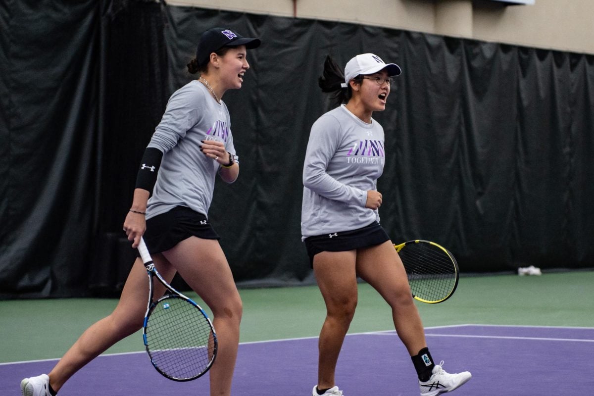 Graduate student Christina Hand and senior Justine Leong celebrate after winning a doubles point. The pairing won 6-0 in Friday’s tilt against Purdue.