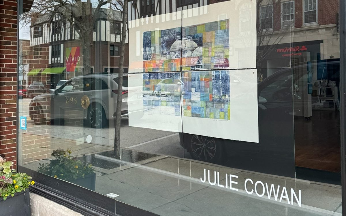 A+gallery+window+displays+a+photo+of+a+painting+and+the+words+Julie+Cowan.