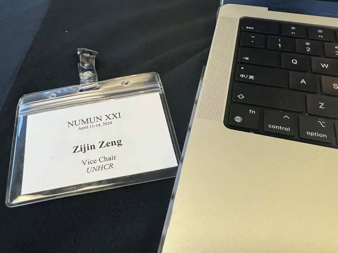 A name tag reading “Zijin Zeng” lies to the left of a laptop.