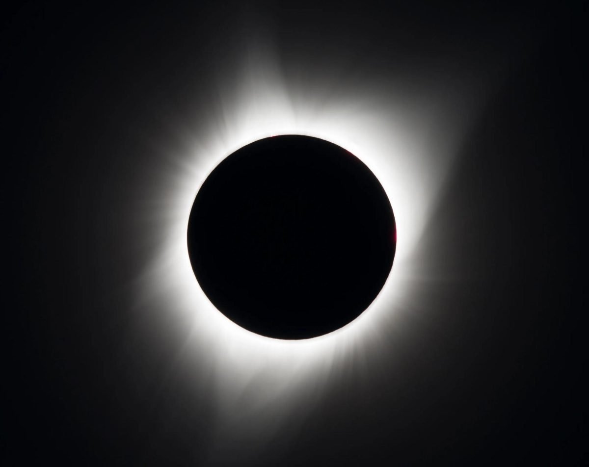 A black circle, representing the moon, is outlined with a white circle, representing the sun, on a black background.