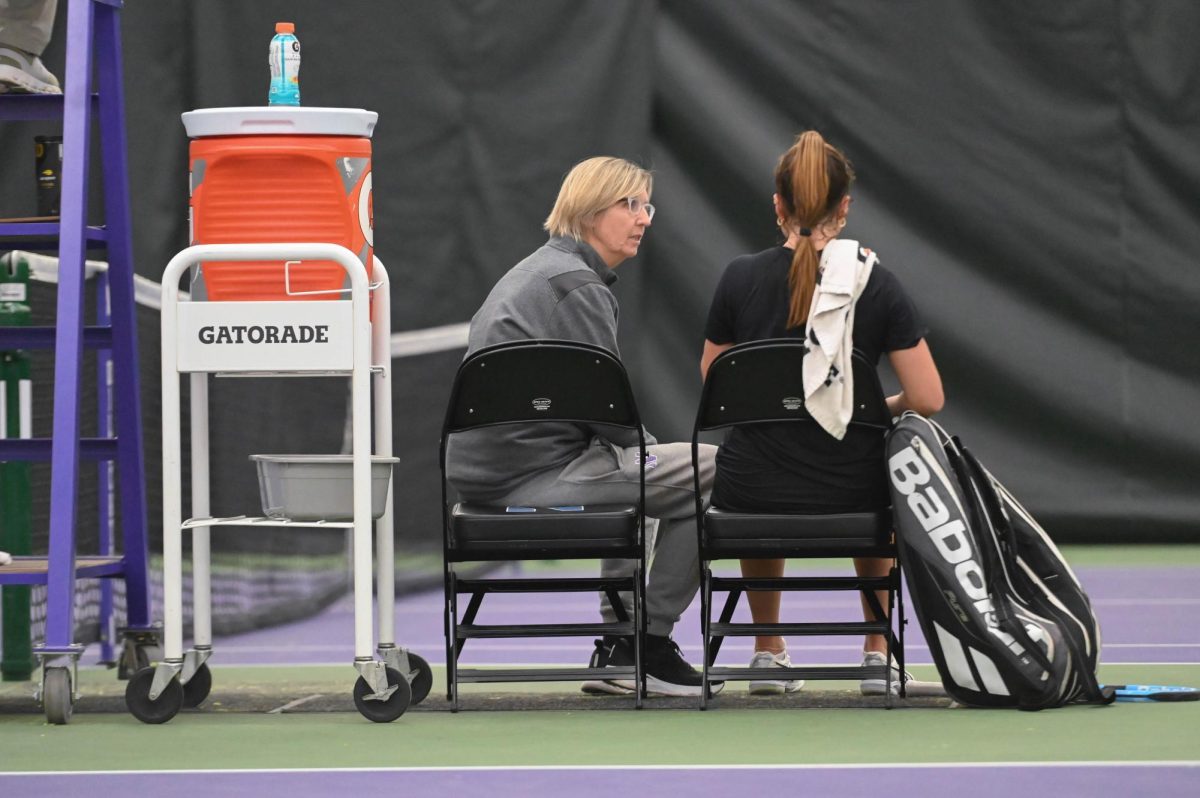 Coach Claire Pollard sits and talks to a tennis player.