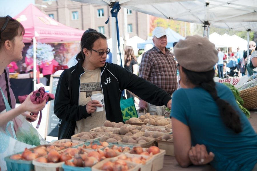 A person points to produce on a table in front of a vendor.