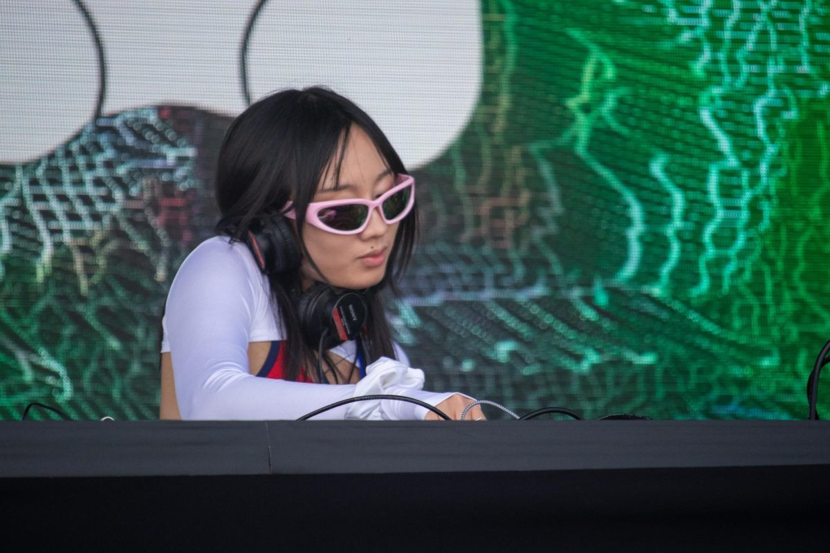 A DJ performs onstage in front of a digital backdrop. 