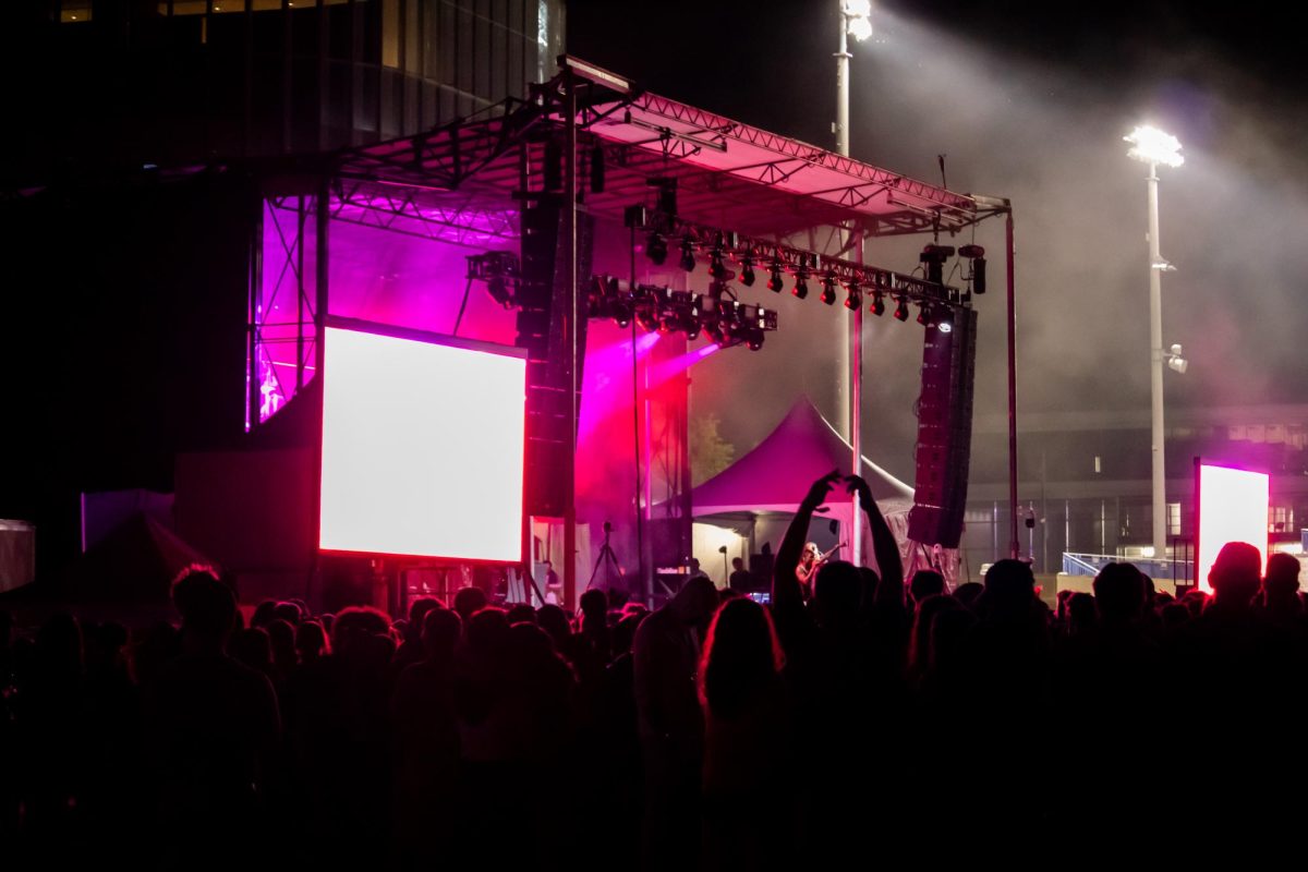 A crowd looks toward a stage at night.