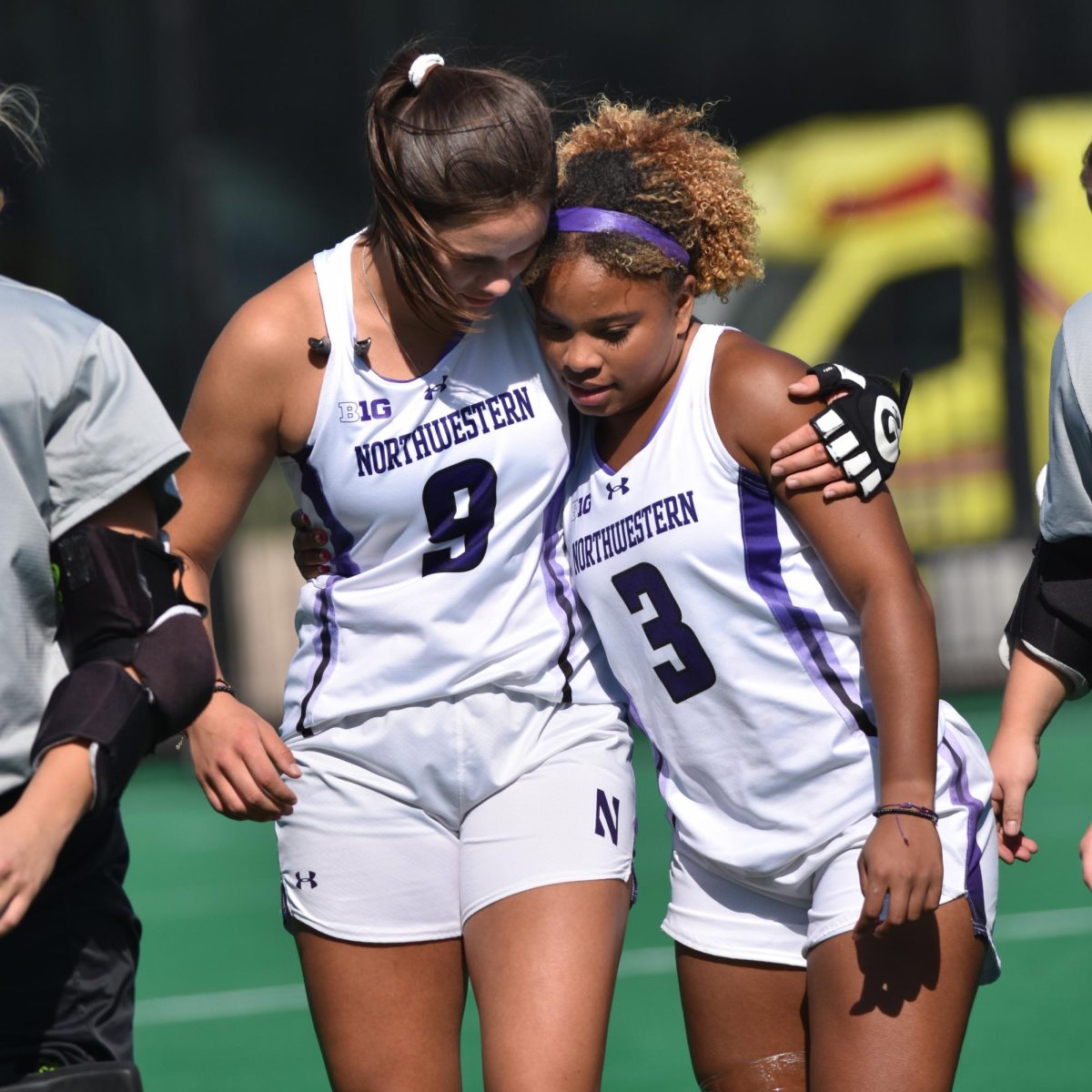 With their arms wrapped around each other, two players walk off the field.