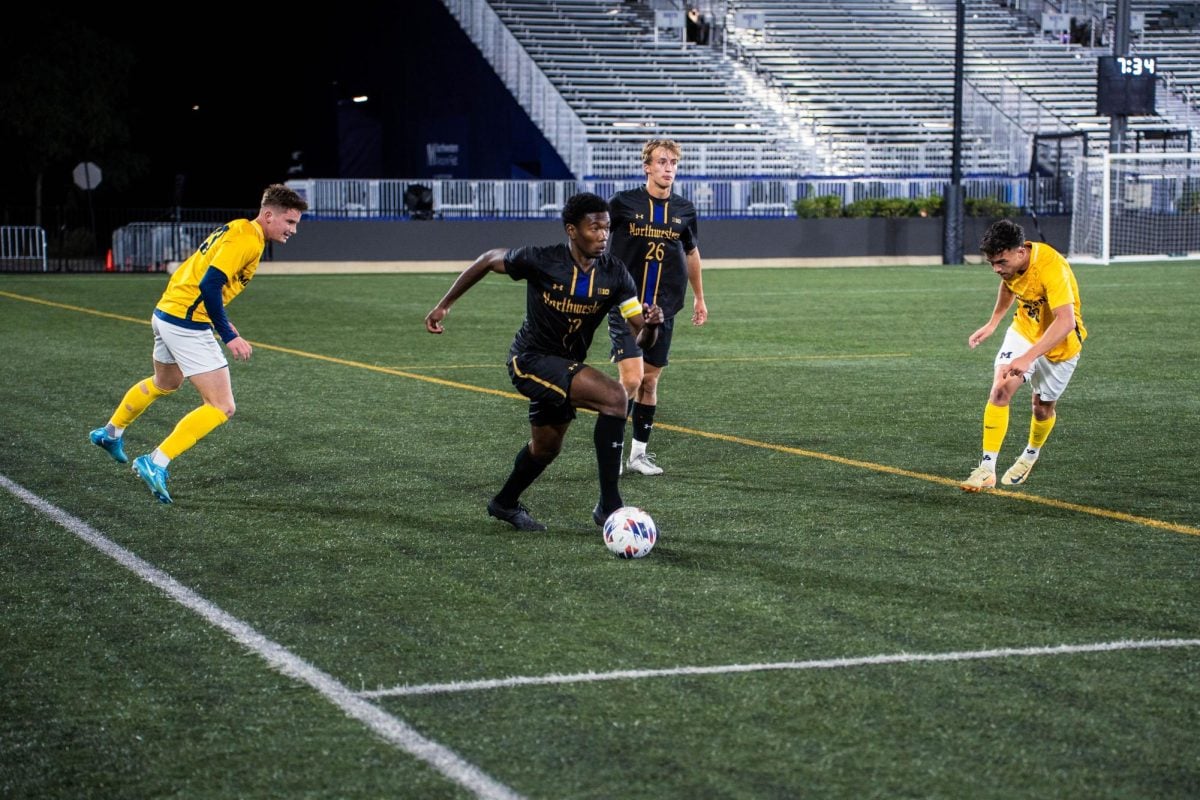 A Northwestern soccer player runs down the field with the ball in front of his feet.