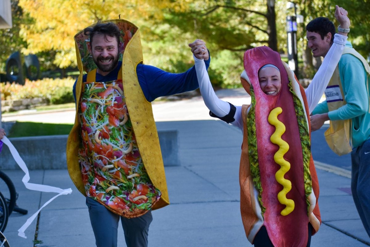 Man dressed as a taco and woman dressed as a hotdog run toward the camera.