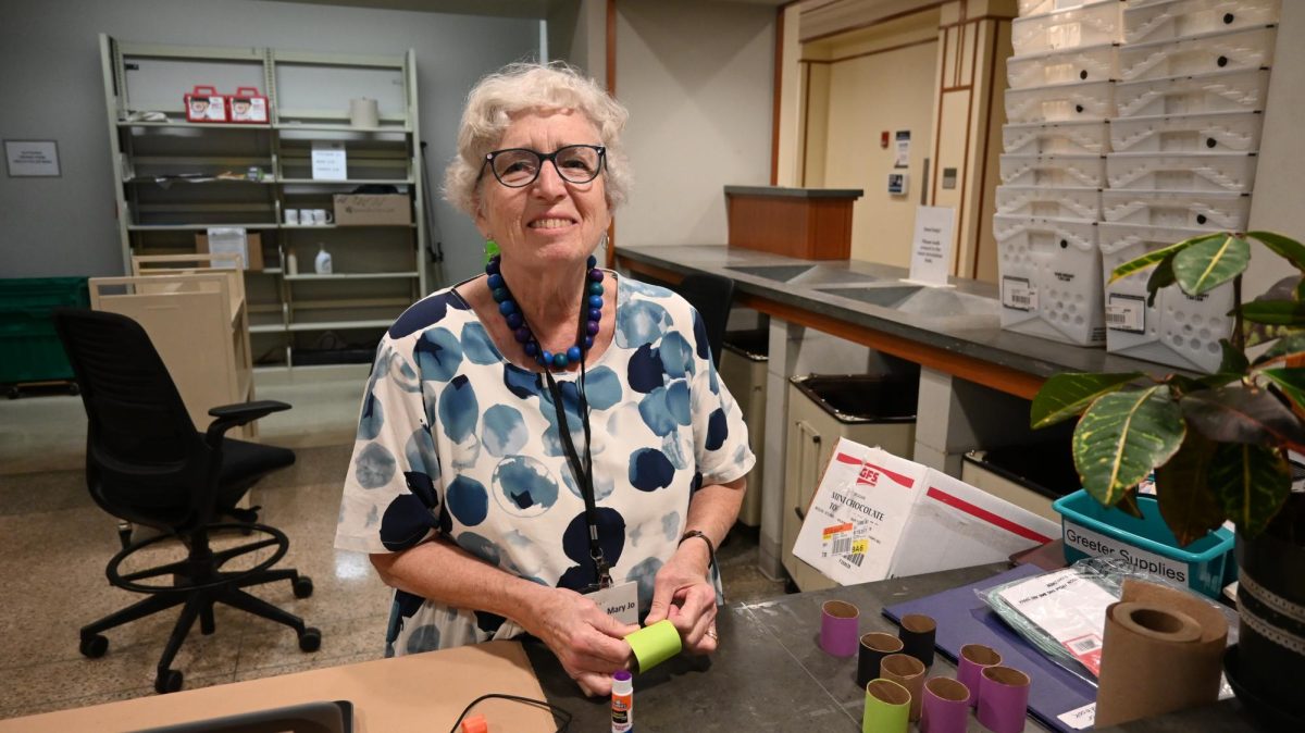 Woman glues colorful paper onto toilet paper rolls for a Halloween craft project at Evanston Public Library.