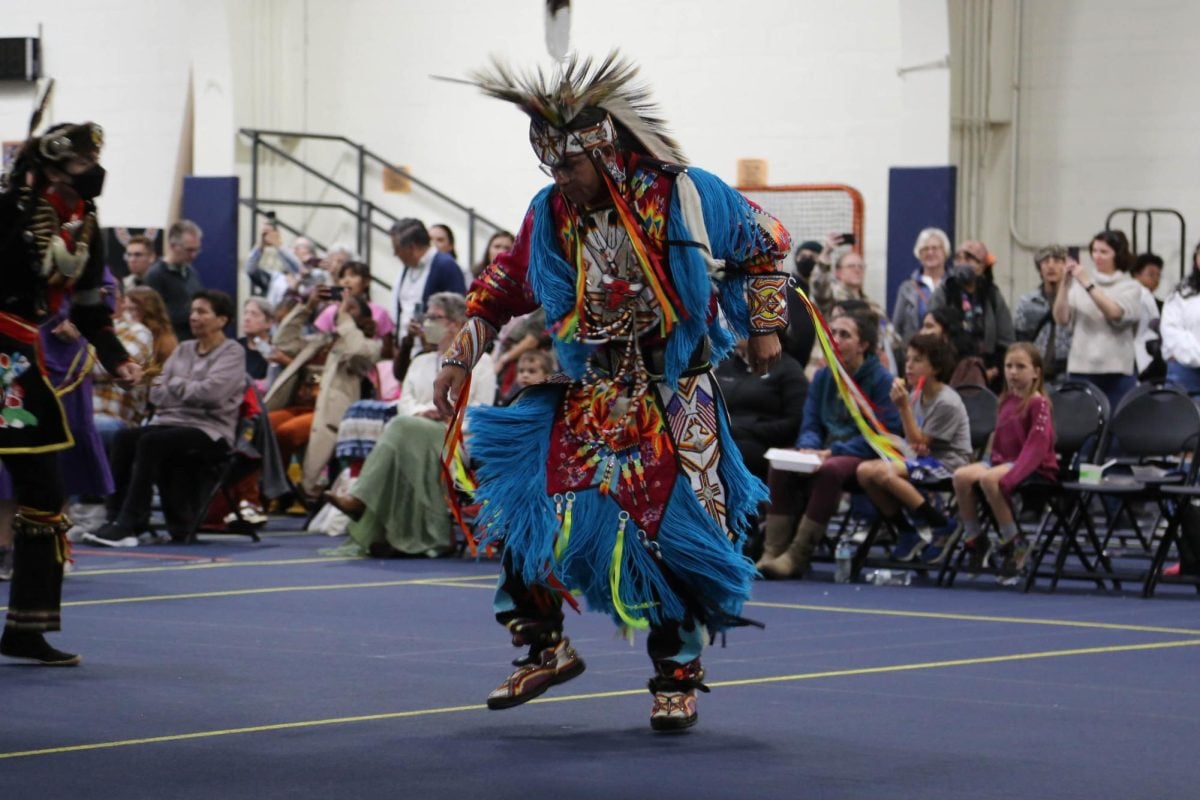 A man in traditional Native American regalia dances.