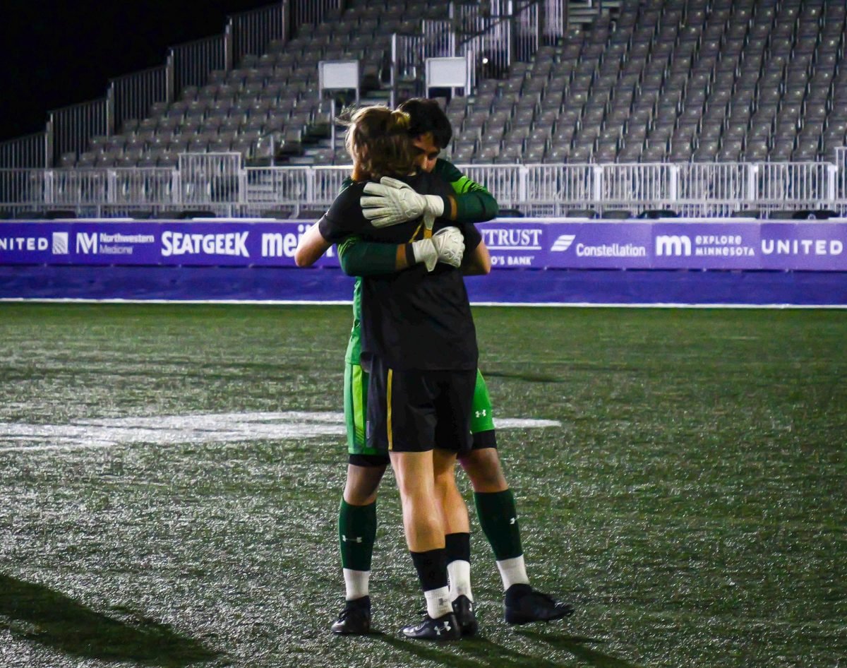 Two Northwestern players, a goalie and a midfielder, hug after winning the game against Michigan.