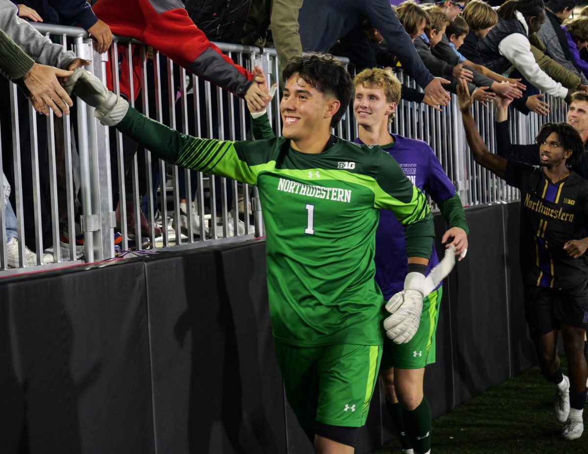 A Northwestern goalie high fives a line of fans after the game, with three other Northwestern players following.