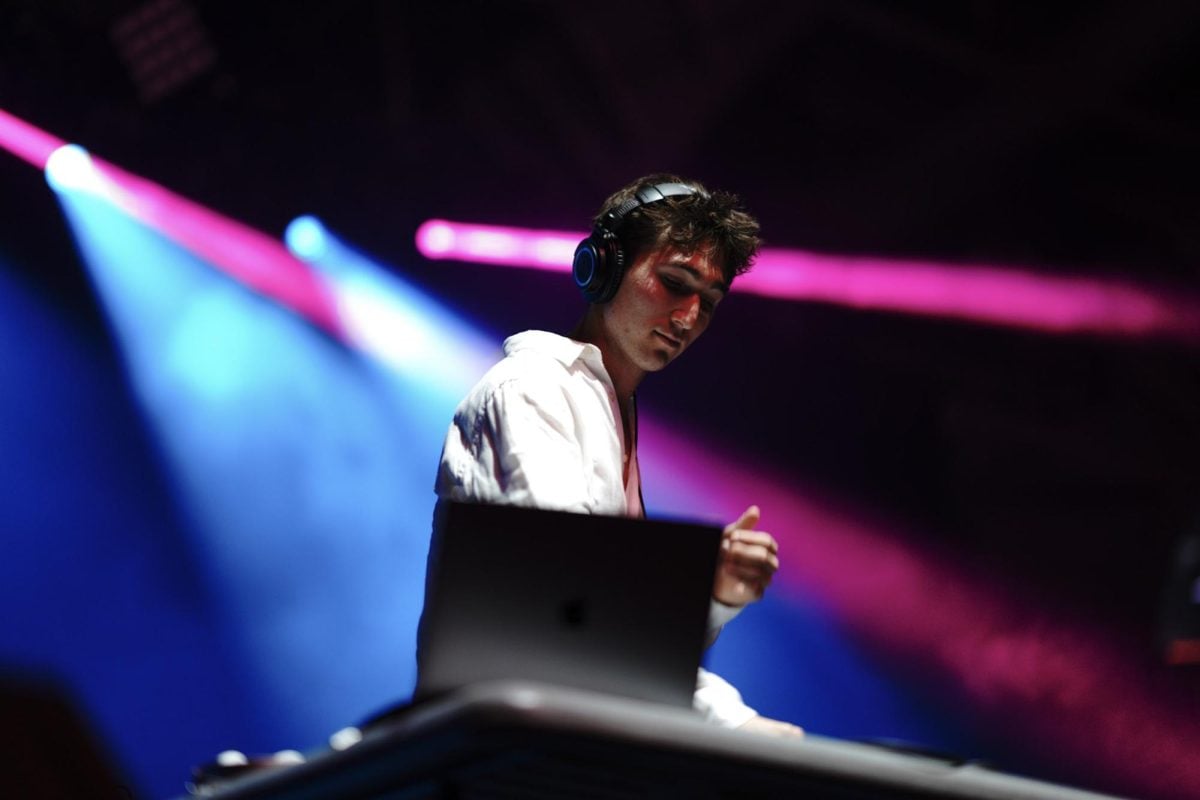 Man performs for audience under blue and pink lights.