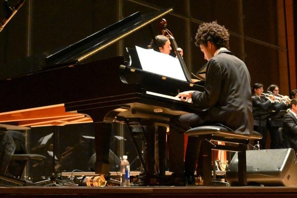 Pianist plays in front of a large group of musicians.