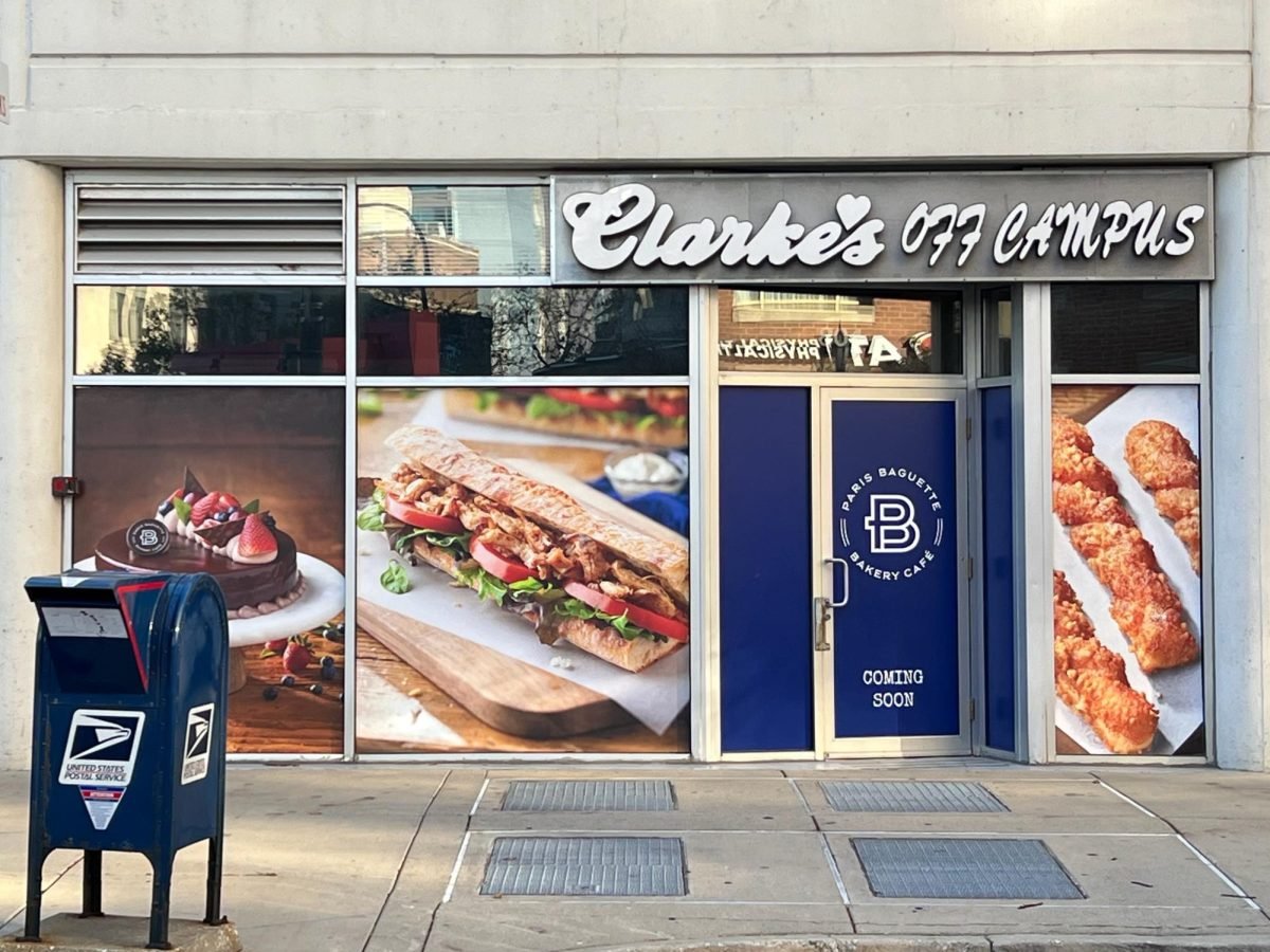 A restaurant storefront displays images of a cake, a sandwich and pastries.