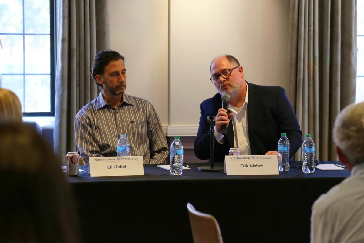 A panelist holds a microphone as he answers a question.