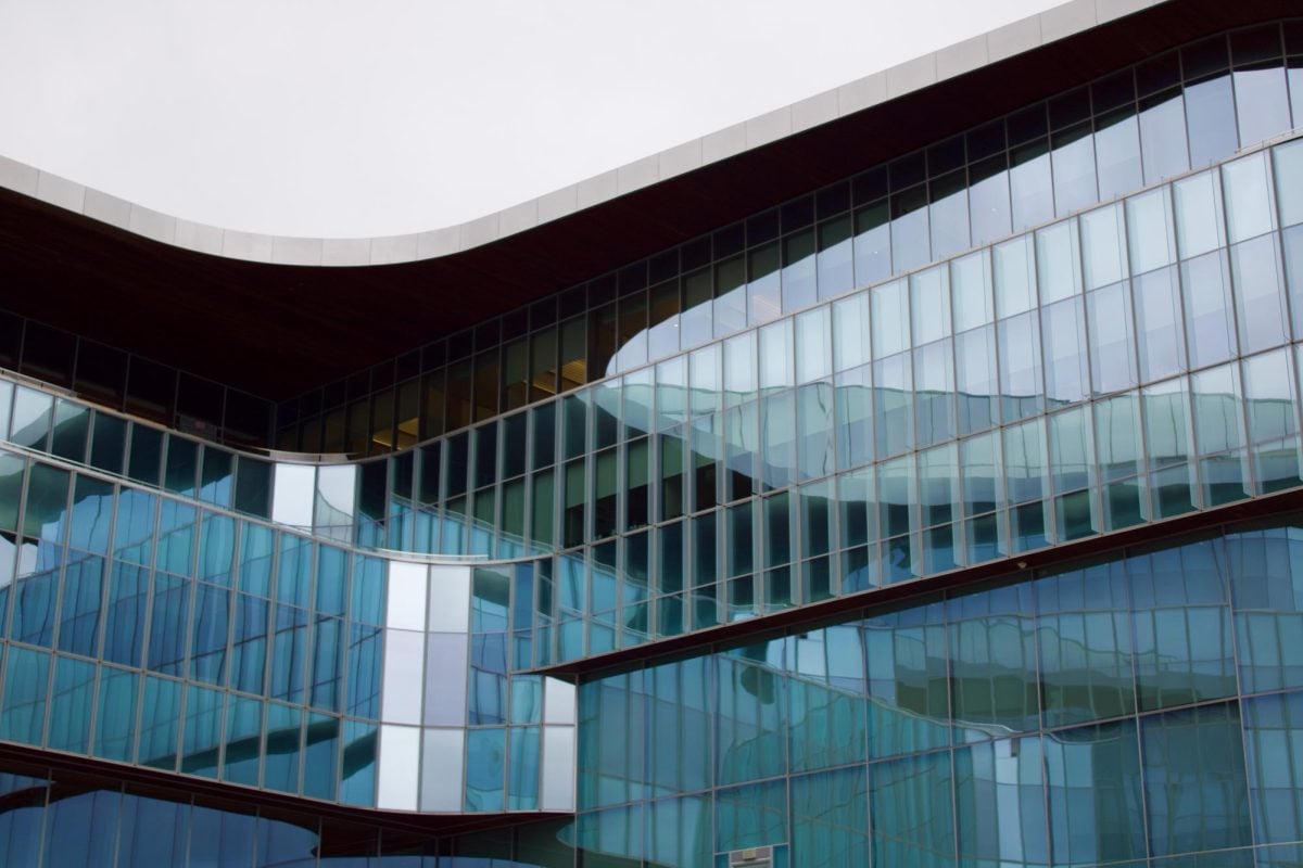 Low angle shot of Kellogg curved section, series of exterior glass windows reflecting other side of building.