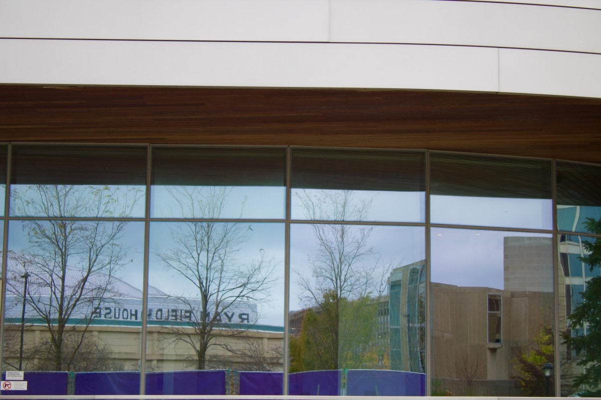 Close-up shot of four exterior glass windows reflecting Ryan Fieldhouse, the indoor football stadium located across Kellogg. 