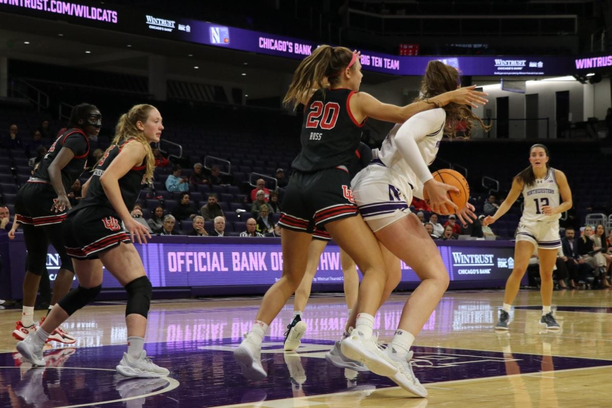 An NU player dribbles basketball as she is guarded by a Utah player.