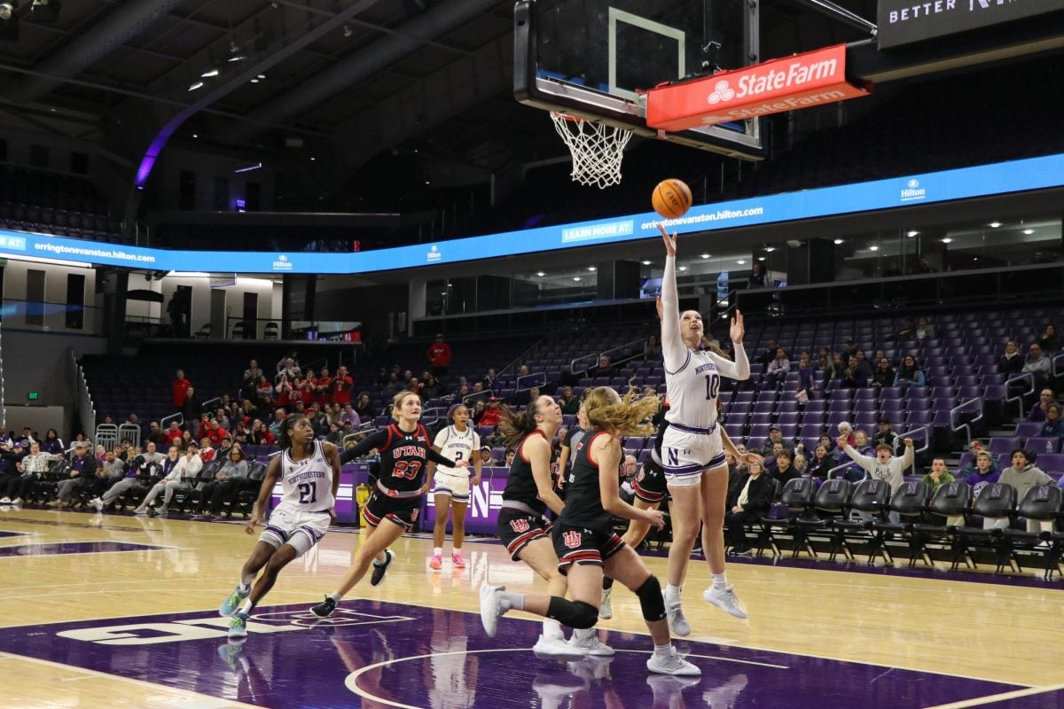 A player shoots a layup while surrounded by opposing team players.