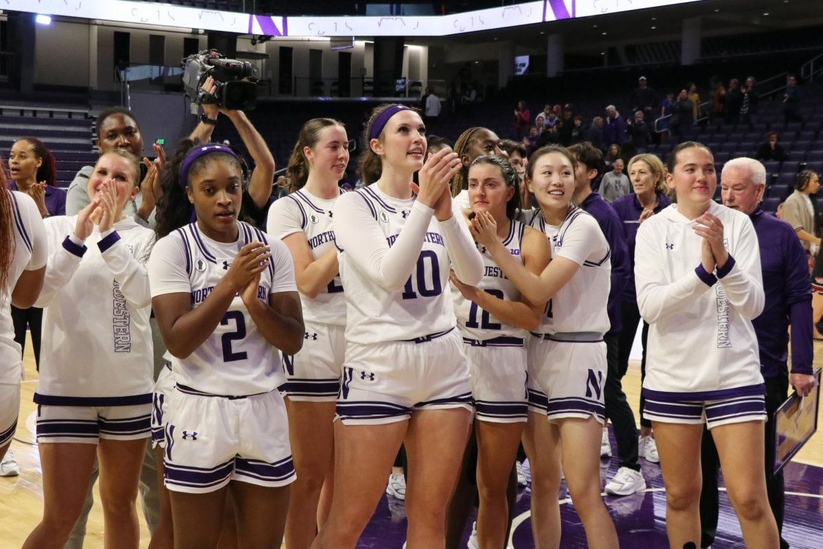 The women’s basketball team stands together and claps.