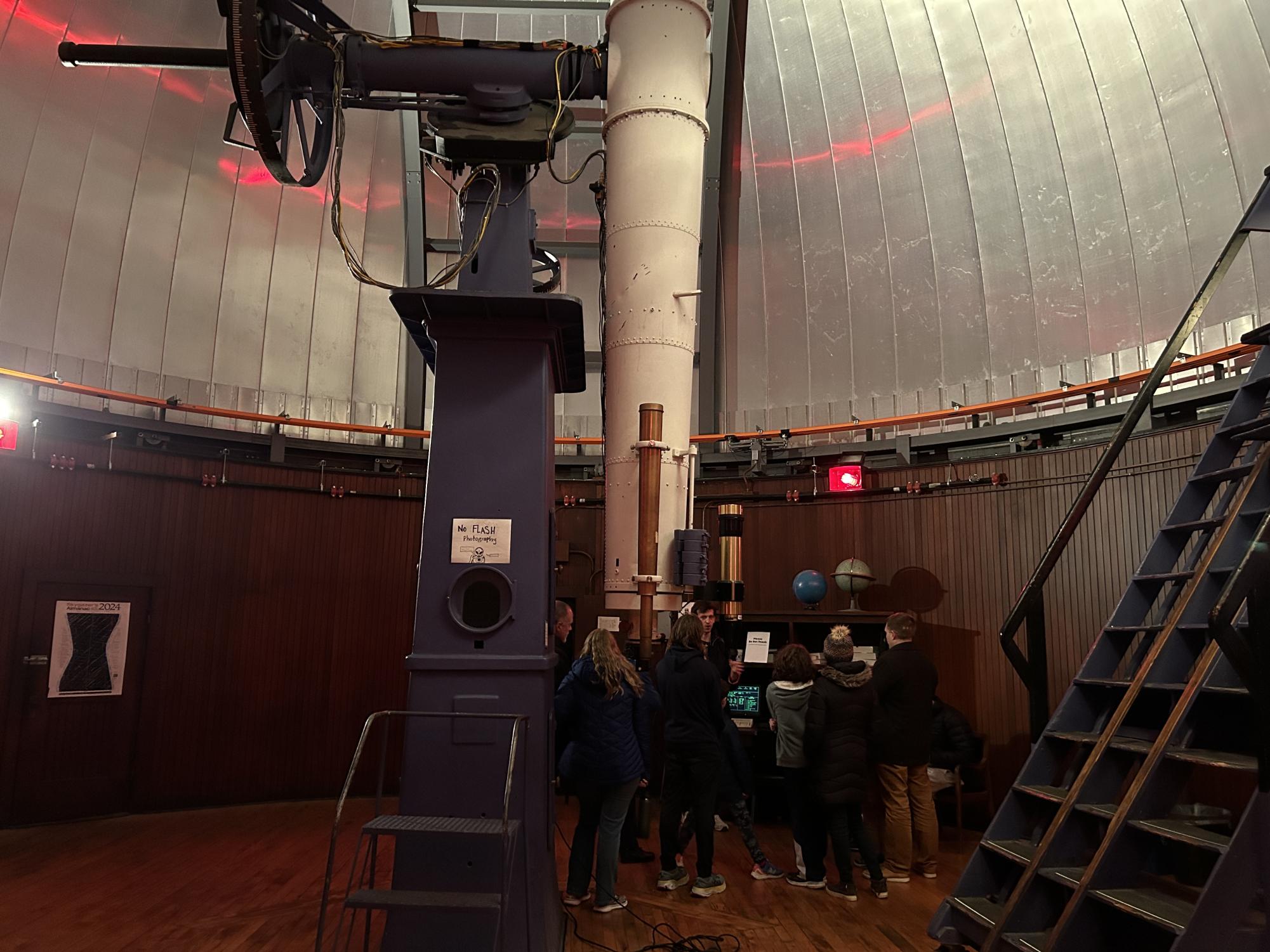 A group of visitors stand around a telescope.