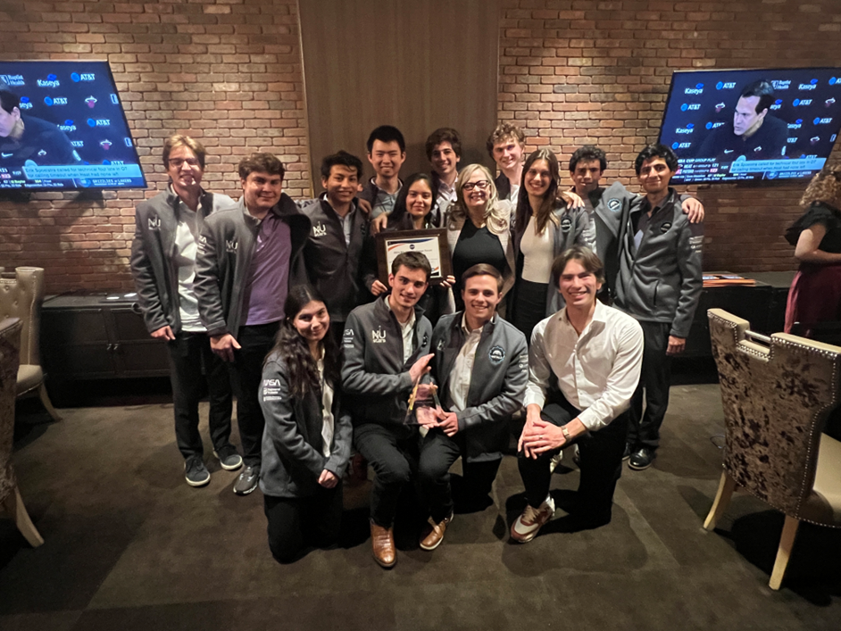 Northwestern Engineering students pose in front of brick wall with Artemis Award plaque at NASA Big Idea Challenge forum