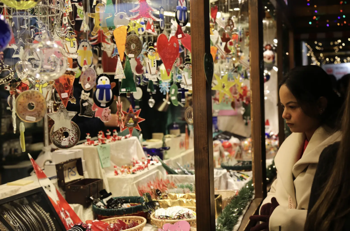 A visitor at Chicago’s Christkindlmarket looks through the window of a booth selling holiday knickknacks.