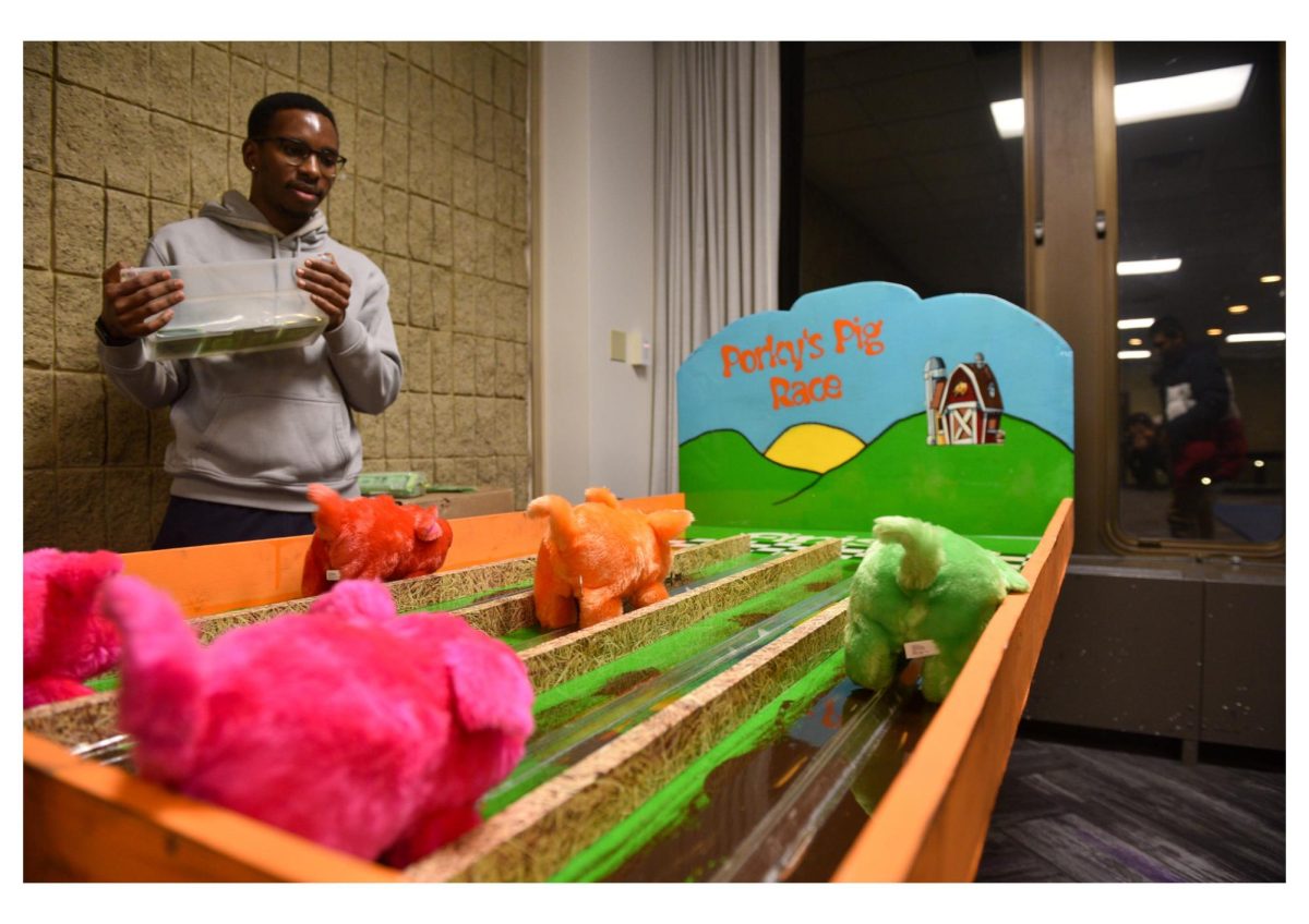 Three battery-powered stuffed pigs race to the finish line of “Porky’s Pig Race” on a tabletop.