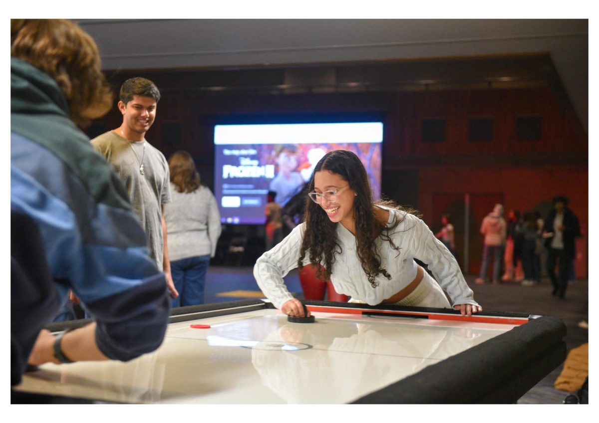 Students participate in a friendly air hockey tournament drawing a crowd of spectators. 