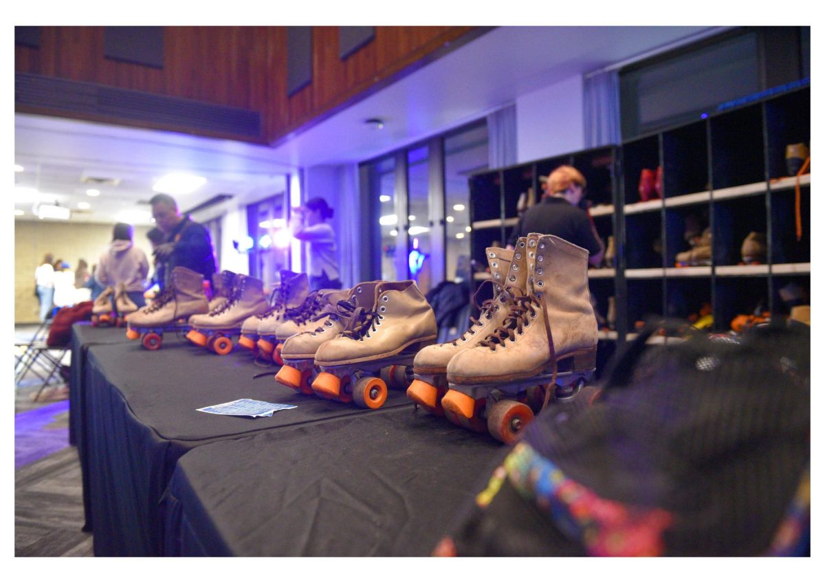Pairs of roller skates sit on a table, available for students to use on an indoor roller skating rink.
