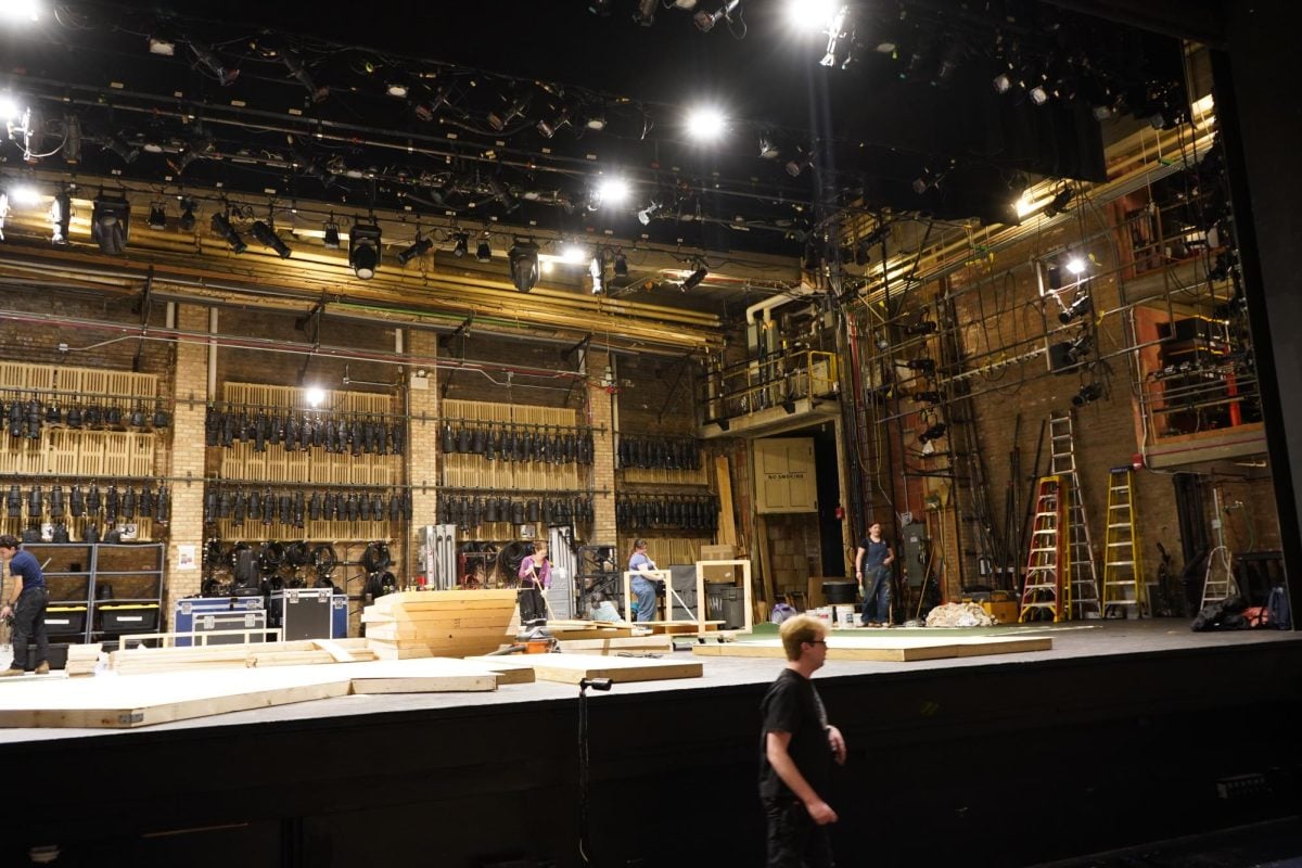 Production members stand on an empty stage assembling set pieces for The Dolphin Show’s ‘Cinderella’