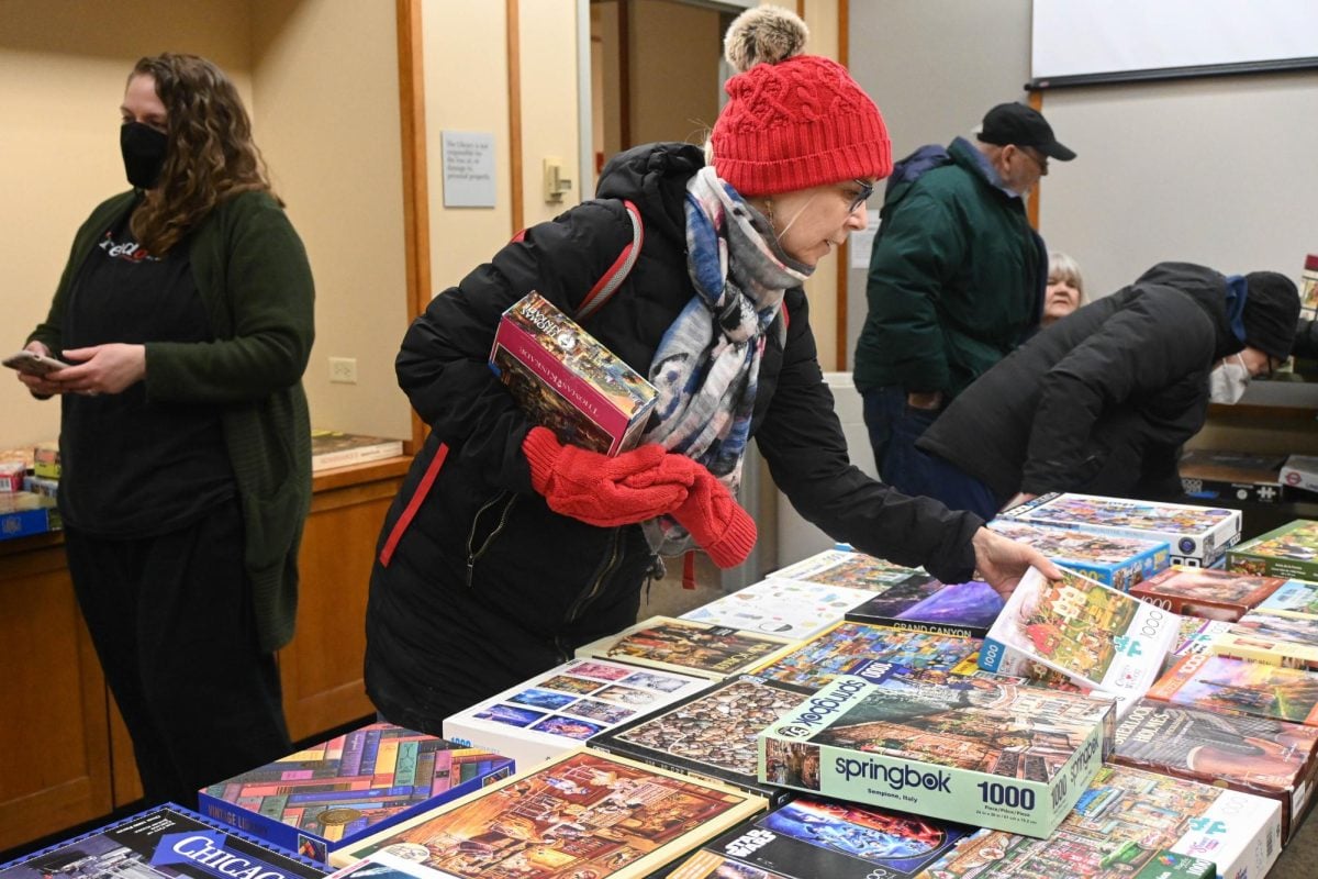 A patron exchanges a puzzle she brought from home with one of the Cookbook &amp; Puzzle Swap’s selections on Tuesday. Games and books are sourced from the public puzzle table on the library’s third floor.