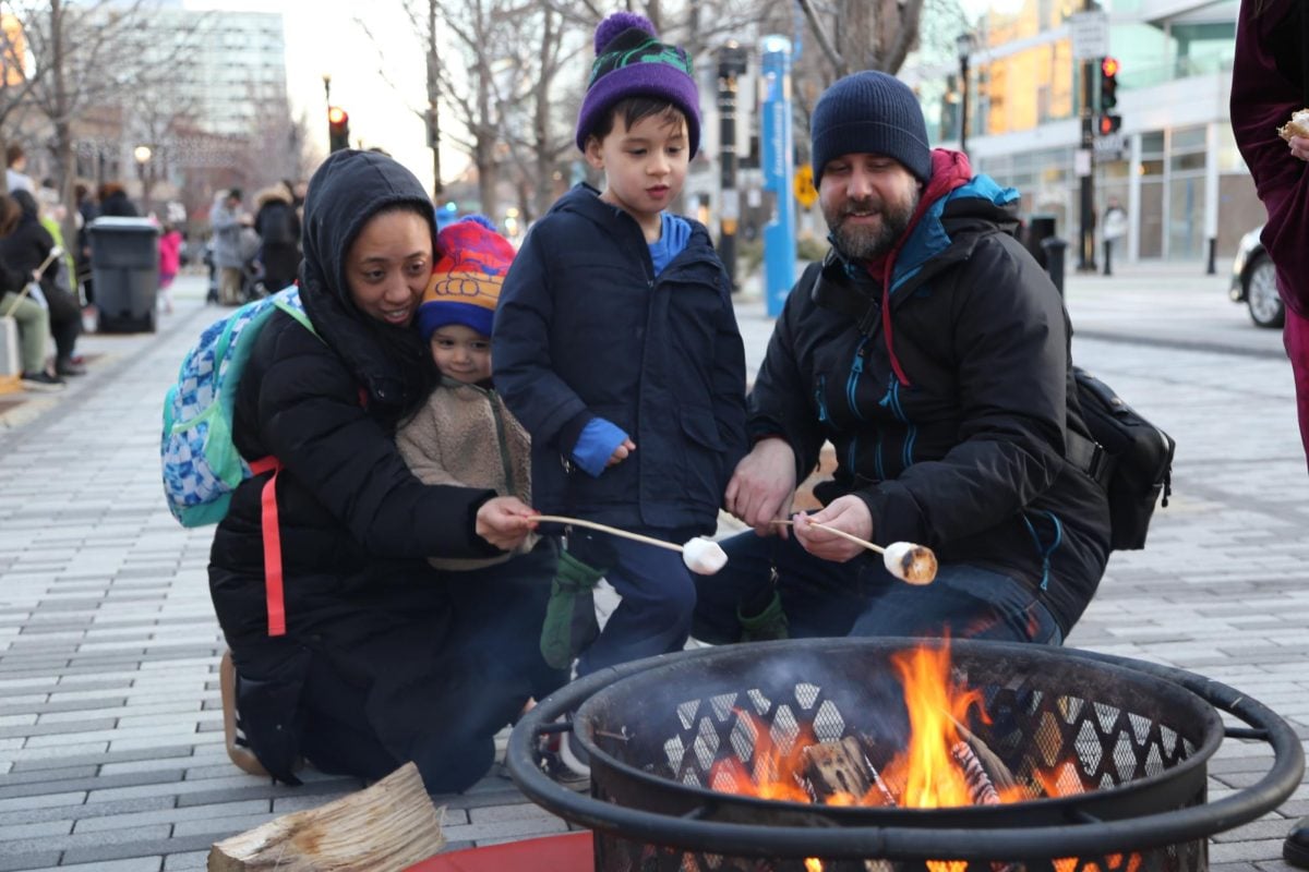 Community members roast marshmallows over a fire pit at Downtown Evanston’s S’mores on the Square event Saturday evening.