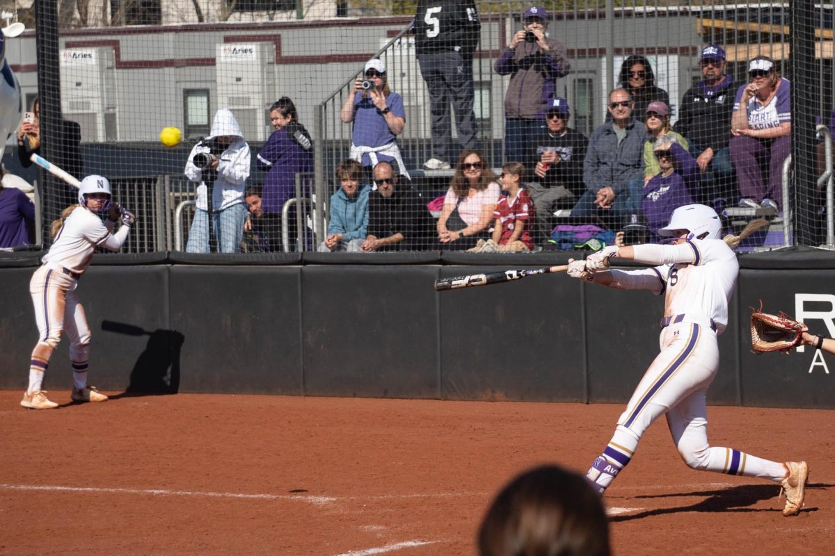 A player swings and hits a softball.
