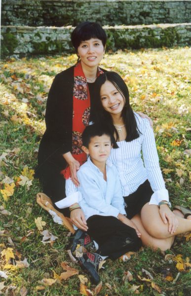 A woman with two children sitting in a field. 