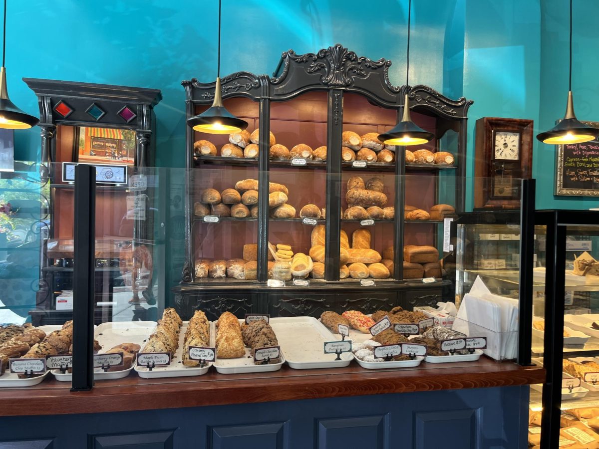 A display case features baked treats with a shelf of different breads behind it