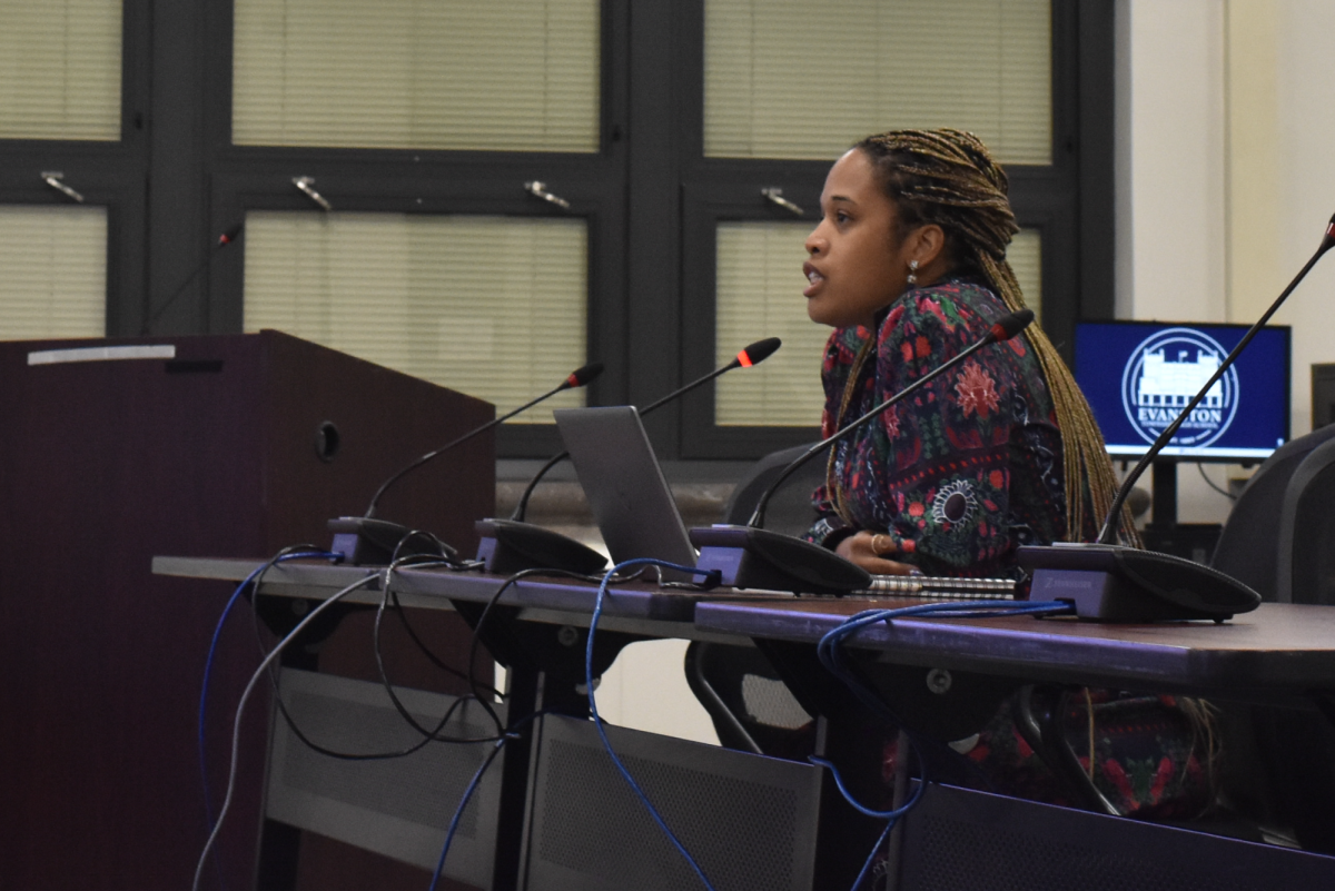 A woman speaks into a microphone at a District 202 meeting Monday night.