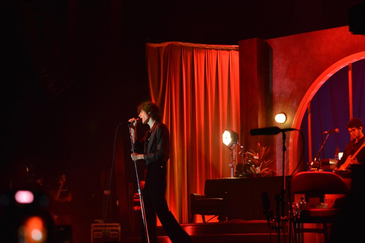 Wide shot of singer gripping the mic stand in red light. 