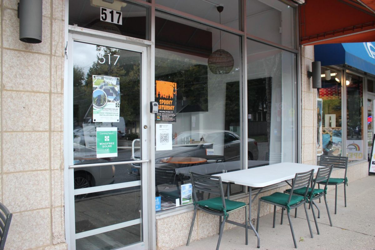 A storefront with a glass door and window and a table in front of it.