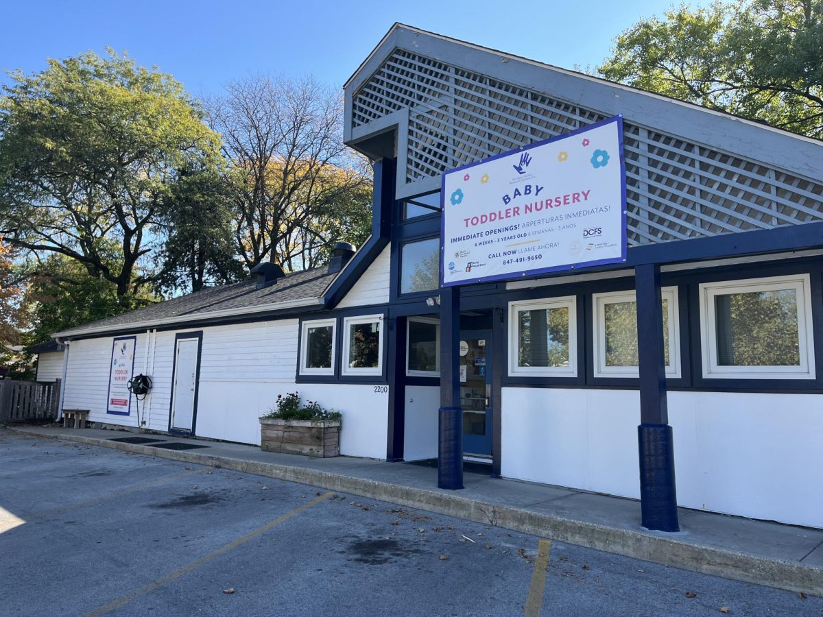 A white and blue one-story building with a sign over the front door advertising IWSE’s Baby Toddler Nursery.