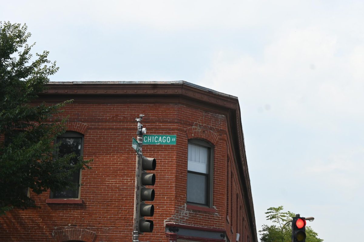 A green sign that says “Chicago Avenue” in front of a brick building.