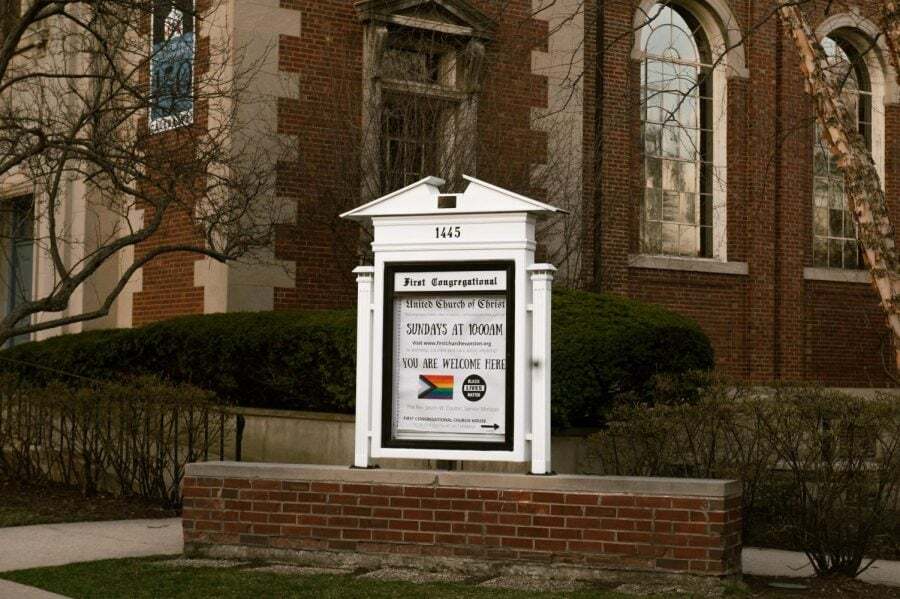 A white sign in front of a brown building.