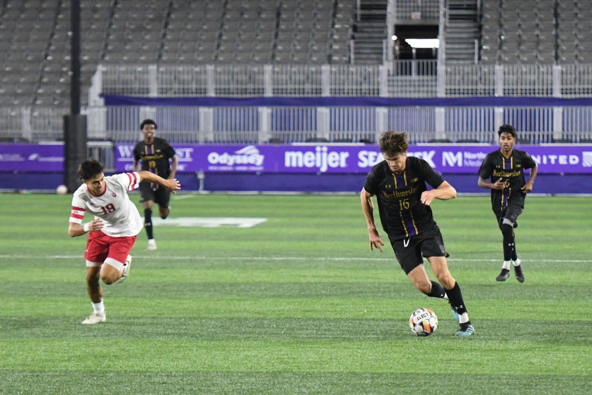 Player in black running with the ball with two players in white to their right